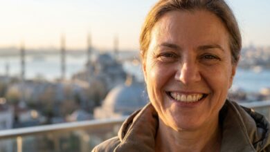 A close-up, photorealistic image of a happy mature person with a perfect smile, with the beautiful, blurred skyline of Istanbul and the Bosphorus visible in the background during a warm sunrise.