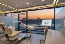 A pristine, modern dental clinic room with an empty patient chair in the foreground and a large window showing a blurred, scenic view of the Istanbul, Turkey skyline at sunset, symbolizing dental tourism.