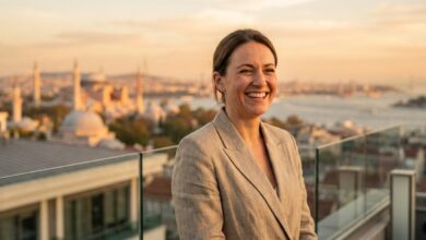 A close-up of a happy, confident person with a perfect white smile, standing on a balcony with a beautifully blurred background of the Istanbul, Turkey skyline at sunset.