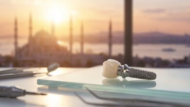 A close-up, detailed photograph of a complete dental implant on a sterile surface inside a modern clinic, with a blurred view of the Istanbul, Turkey skyline through a window in the background.