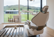 Close-up of sterile, modern dental instruments on a tray in a pristine dental clinic, with a blurred, soft New Zealand landscape visible through a window in the background, conveying professional dental care without any text.
