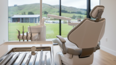 Close-up of sterile, modern dental instruments on a tray in a pristine dental clinic, with a blurred, soft New Zealand landscape visible through a window in the background, conveying professional dental care without any text.