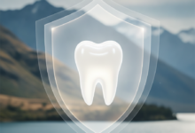 A gleaming, pristine white tooth at the center, symbolizing dental health and protection. Surrounding it are soft, abstract, blurred light patterns that convey financial security. In the very soft-focus background, a majestic, blurred New Zealand landscape, possibly mountains or fjords, under clear skies. The image is clean, bright, and free of any text.