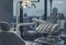 A photorealistic image showing a clean, modern dental examination room with a state-of-the-art dental chair and sterile instruments, against a blurred background of the Auckland city skyline with the Sky Tower.