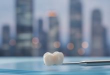 Close-up, photorealistic image of a polished zirconia dental crown, appearing naturally translucent, resting on a sterile, light-colored dental tray. The background is an extremely blurred, cool-toned urban cityscape at dusk, hinting at a modern professional clinic setting. The crown is sharply in focus, emphasizing its detail and quality.